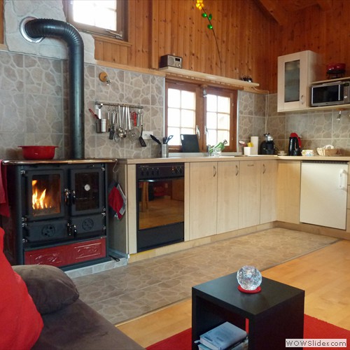 Wohnzimmer mit Holzofen und Einbaukueche